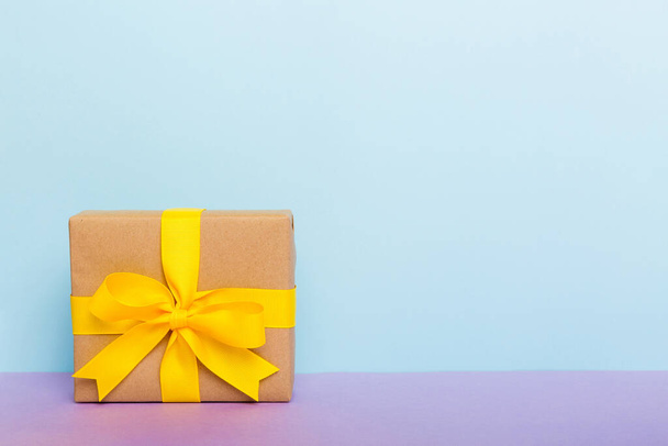 holiday paper present tied yellow ribbon bow top view with copy space. Flat lay holiday background. Birthday or christmas present. Christmas gift box concept with copy space. - Φωτογραφία, εικόνα