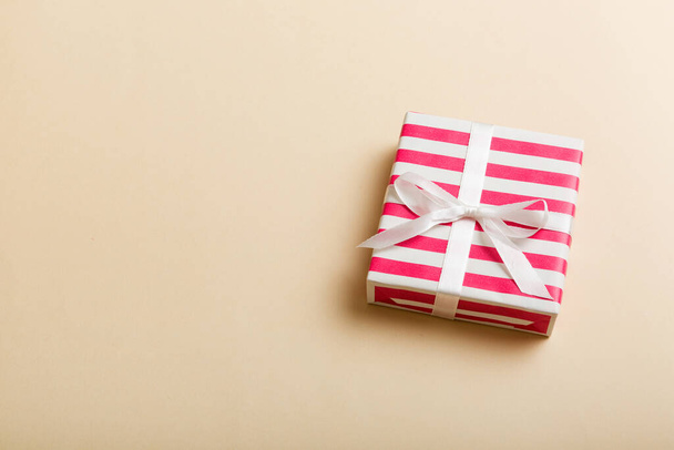 csomagolt karácsonyi vagy más ünnep kézzel készített ajándékdoboz színes papír szalaggal színes háttér. Jelen doboz, díszítés ajándék színes asztalon, felülnézet másolási hellyel. - Fotó, kép