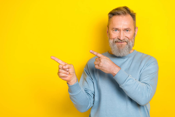 Photo of positive aged person indicate fingers empty space isolated on yellow color background. - Valokuva, kuva