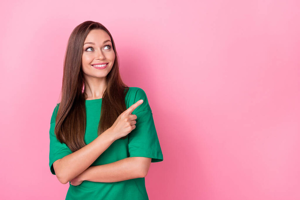 Portrait of nice cute optimistic woman straight hairdo dressed green t-shirt directing look empty space isolated on pink color background. - Фото, изображение