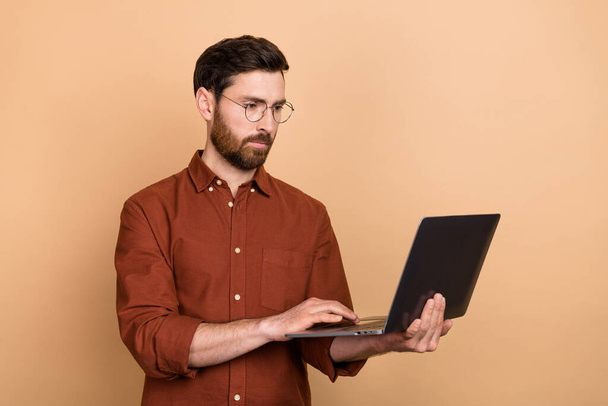Ritratto di persona concentrata calma tenere netbook scrivere digitando messaggio isolato su sfondo di colore beige. - Foto, immagini