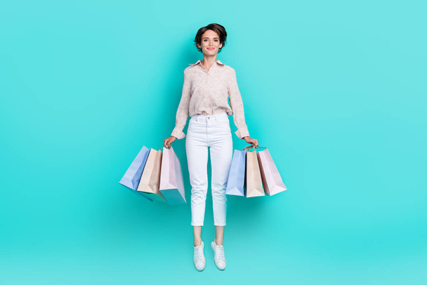 Full size photo of satisfied lady fashionista stylish trendy clothes hand hold bag big sale empty space isolated on cyan color background. - Foto, afbeelding