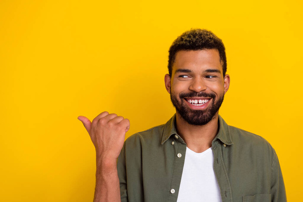 Photo of dreamy cute man wear khaki shirt pointing thumb looking empty space isolated yellow color background. - Φωτογραφία, εικόνα