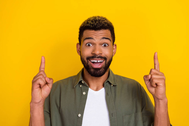 Photo of funny impressed man wear khaki shirt pointing up empty space isolated yellow color background. - Fotografie, Obrázek