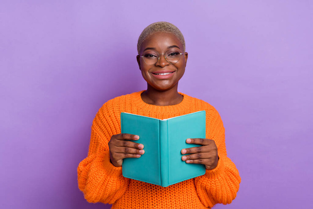 Photo of attractive young lady hold book study dressed trendy fall orange knitwear pullover spectacles isolated on violet color background. - Fotoğraf, Görsel