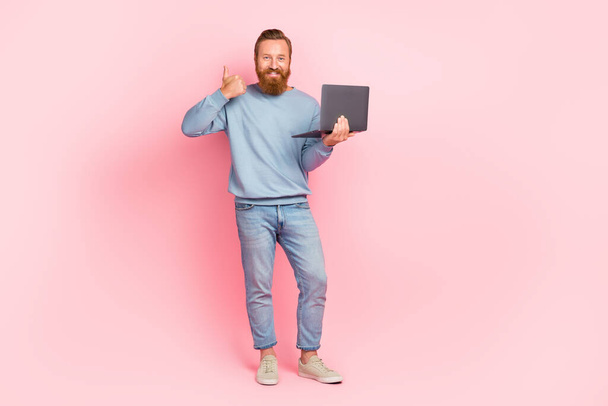 Full size portrait of cheerful guy demonstrate thumb up feedback hold netbook isolated on pink color background. - Фото, зображення