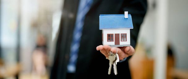 Агент по недвижимости предоставляет модель дома и ключи покупателю. banner - Фото, изображение