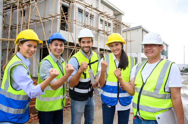 Group of contractors, engineers and formats in safety vests with helmets hands up to work together to successfully complete a construction project on construction site. cooperation and success concept - Fotoğraf, Görsel