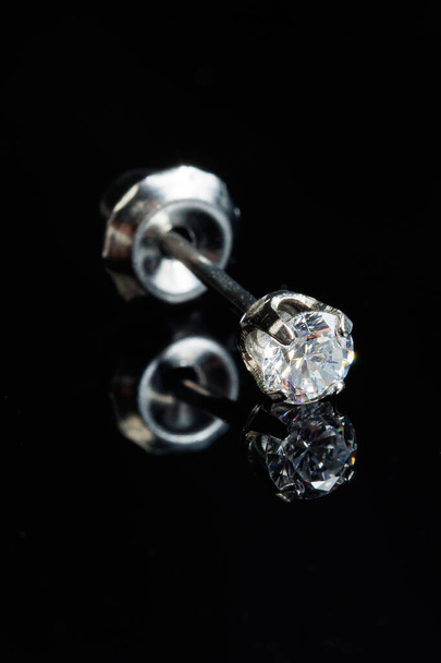 Silver earring macro photo with a precious stone on a black isolated background - 写真・画像