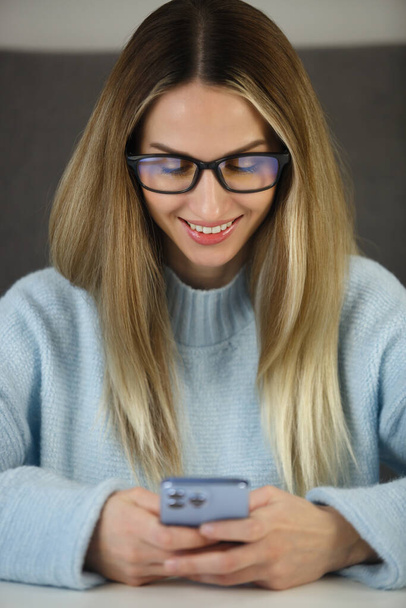 Happy white woman typing sms message on mobile phone. Cheerful female person communicating online on smartphone app - Фото, изображение