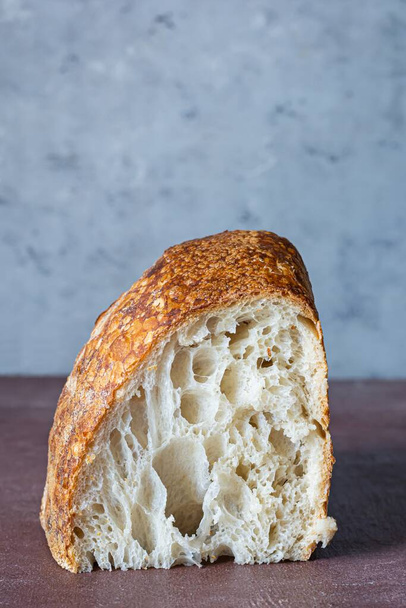 Friss házi kovászos kenyér teljes kiőrlésű liszttel, szürke-barna alapon. Egészséges élelmiszer. - Fotó, kép