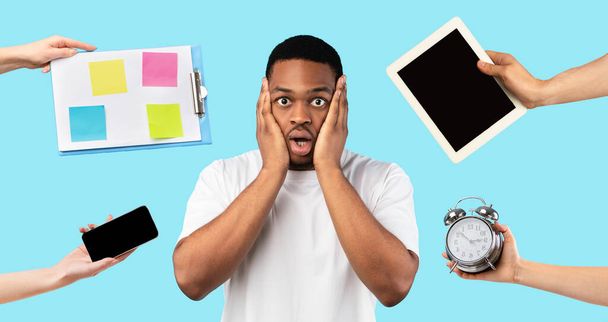 Zeitmanagement-Konzept. Schockierter junger Schwarzer, der sein Gesicht berührt, viel zu tun hat, Hände mit Gadgets, Zeitplan und Alarm um ihn herum, blauer Hintergrund, Collage - Foto, Bild