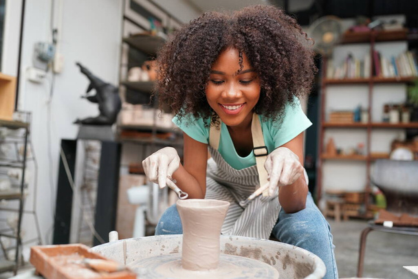 Joven alfarero de mano afro haciendo jarrón de arcilla en taller de cerámica, propietario de negocios.  - Foto, Imagen