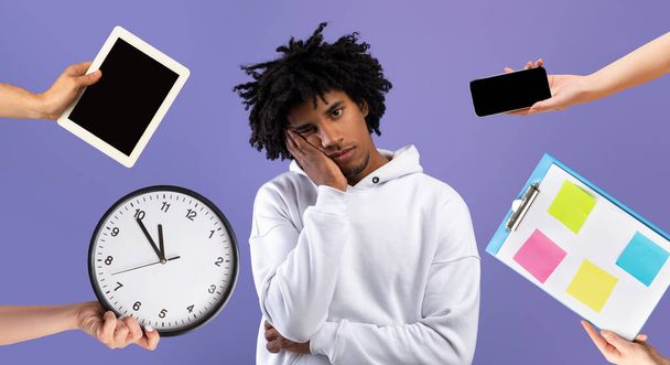Time management concept. Exhausted african american millennial guy touching his face, having lot things to do, hands with gadgets, schedule and watch around him, blue background, collage - Photo, Image