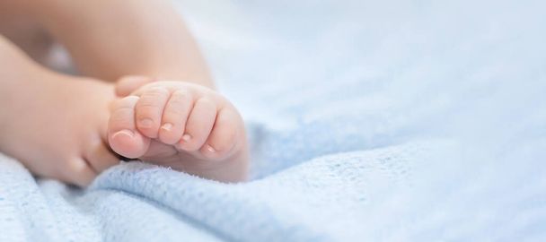 赤ん坊の足は青い毛布の上にある。赤ちゃんの健康。足の運動能力,ウェブバナー,コピースペース - 写真・画像
