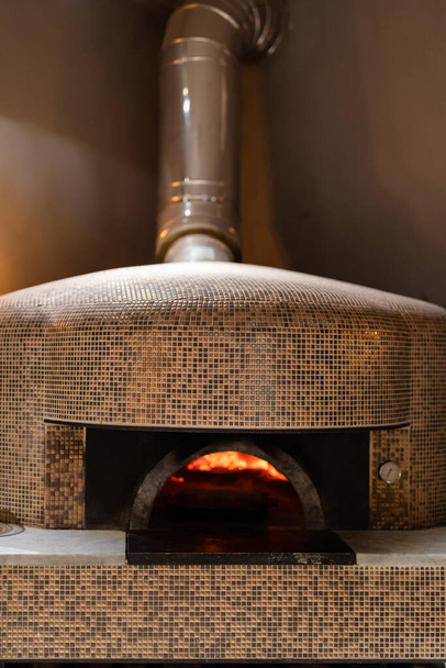 Pizza concept. Preparing traditional italian pizza. Long shovel for pizza, baking dough in a professional oven with open fire in interior of modern restaurant kitchen - Zdjęcie, obraz