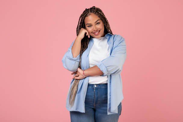 Cheerful Black Female Posing Touching Face Smiling To Camera On Pink Background. Studio Shot Of Braided Plus Size Woman. Beauty And Body Positive Concept - Foto, imagen