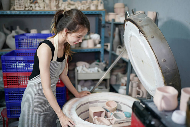 Beautiful woman making ceramic pottery on wheel, hands close-up. Concept for woman in freelance, business, hobby - Фото, изображение