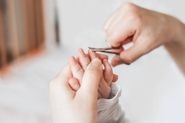 Мама стрижет детские ногти специальными детскими ножницами дома. Закрывай. скопировать пространство. маникюр для новорожденных. белый фон - Фото, изображение