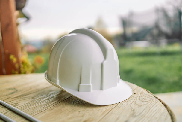White helmet hard hat on wood floor in constriction site.  - Фото, изображение