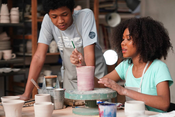 Νεαρό Afro κορίτσι και αγόρι στο εργαστήριο κεραμικής, ιδιοκτήτης επιχείρησης.  - Φωτογραφία, εικόνα