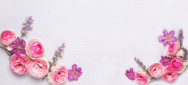Banner with pink roses and violet summer clematis flowers on grey textured background. Place for text. Flat lay.   - Foto, Imagem