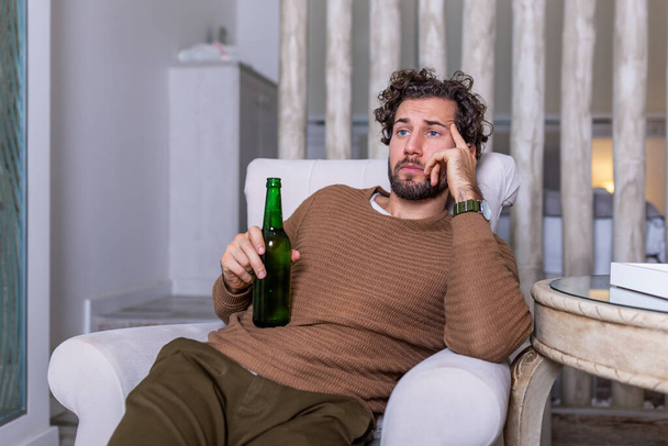 悲しいスポーツファンはソファに座って、試合を失う彼のチームとテレビで試合を見ています。サッカーやサッカーの試合をテレビで観ながらビールを飲みながら - 写真・画像