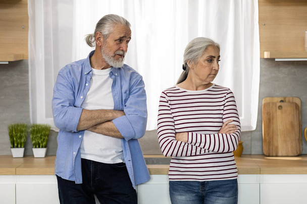 Reconciliation Concept. Loving Elderly Man Talking To His Offended Wife While They Standing Together In Kitchen After Argue At Home, Senior Spouses Having Relationship Problems, Free Space - 写真・画像