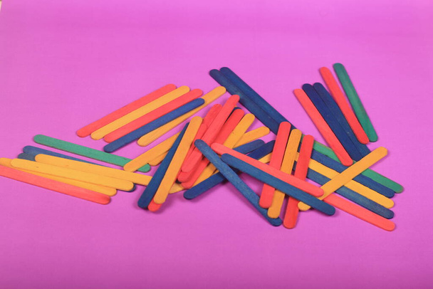 colorful popsicle sticks on purple background - Foto, afbeelding