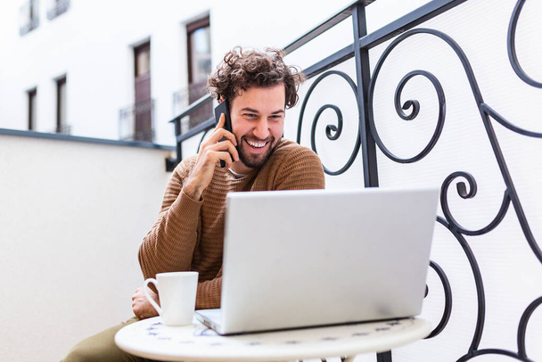 young man working from home using smart phone and notebook computer.Portrait of businessman talking on mobile phone and drinking coffee in the morning - Photo, image