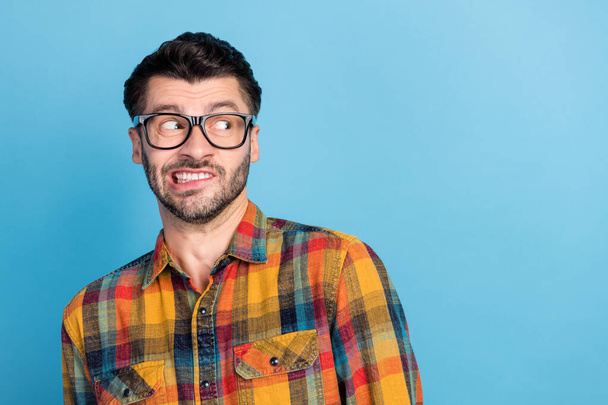 Photo of horrified handsome stylish man in glasses dressed checkered shirt looking at empty space isolated on blue color background. - Valokuva, kuva