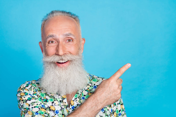 Photo of excited funny man pensioner dressed flower print shirt pointing finger empty space isolated blue color background. - Photo, image