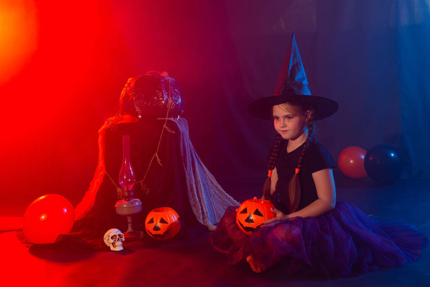 Funny girl child kid in halloween costume witch playing with spooky jack pumpkins fog and jack russell terrier dog. - Photo, image