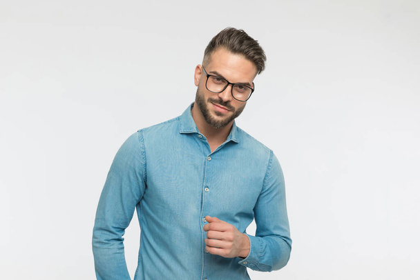 retrato de un hombre guapo y casual posando con las gafas puestas y una pequeña sonrisa en la cara - Foto, imagen
