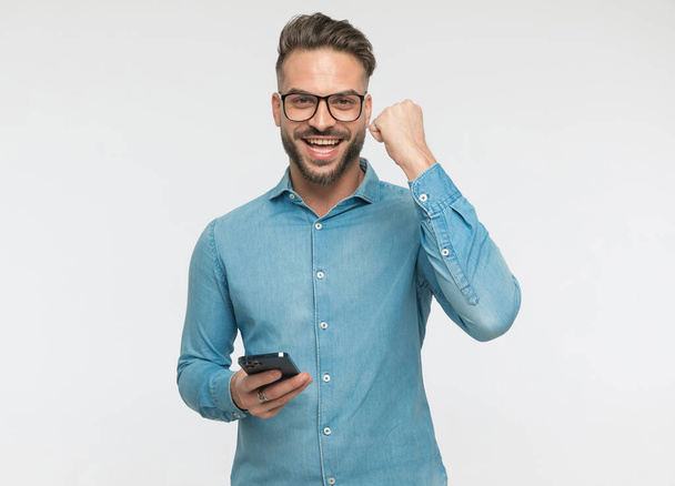 handsome casual man celebrating success after the great news he received over the phone - Photo, Image