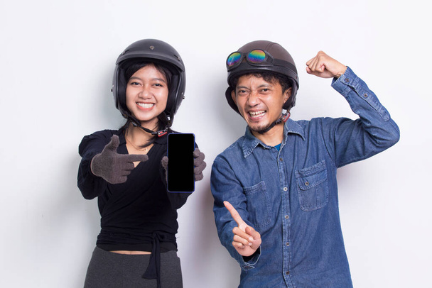 Young asian couple with a motorcycle helmet demonstrating mobile cell phone isolated on white background - Photo, Image