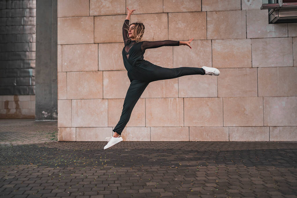 Young girl doing gymnastic jump on the street. Urban contemporary dance concept. stock photography - Fotó, kép