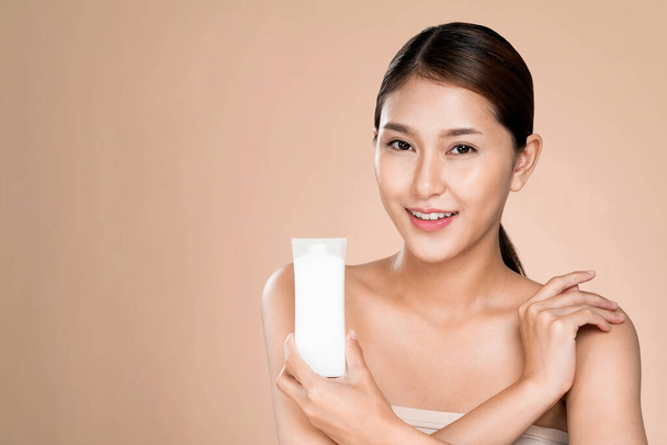 Ardent woman smiling holding mockup product for advertising text place, light grey background. Concept of healthcare for skin, beauty care product for advertising. - Foto, Imagen