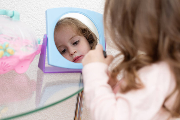 Cute little girl with lipstick applying makeup, glamour kid - Foto, imagen