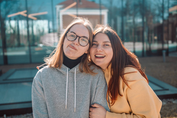 Herbst-Outdoor-Porträt von zwei Freunden lustige Mädchen beim Fotografieren mit einem Smartphone bei hellem Sonnenuntergang. Gruppe glücklicher Frauen macht Selbstporträt im Urlaub  - Foto, Bild