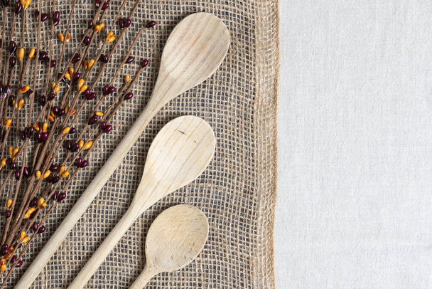 kookconcept met houten lepels en bessen twijgen op twee derde jute en een derde linnen achtergronden - Foto, afbeelding