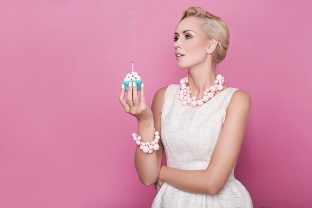 Beautiful women with cream dress holding small cake with colorful candle. Birthday, holiday - Fotó, kép