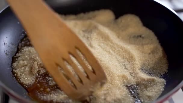 Коричневий цукор в гарячій сковороді на вогні сповільнюється нагрівання і танення і змішується з дерев'яною ложкою
 - Кадри, відео