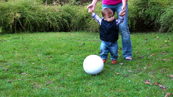Милий маленький хлопчик грає з футбольним м'ячем, підтримуваний його матір'ю
 - Кадри, відео