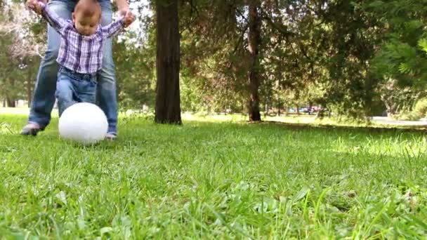Χαριτωμένο μικρό αγόρι που παίζει με μπάλα ποδοσφαίρου που υποστηρίζεται από τη μητέρα του - Πλάνα, βίντεο