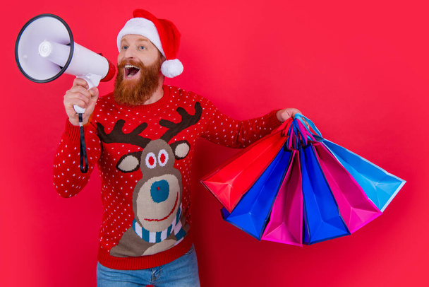 Bearded Santa shouting to loudspeaker holding shopping bags. Happy man making holidays discount announcement. Christmas sale announcement. Shop announcement. Merry Christmas. Happy New Year. - Foto, Imagem