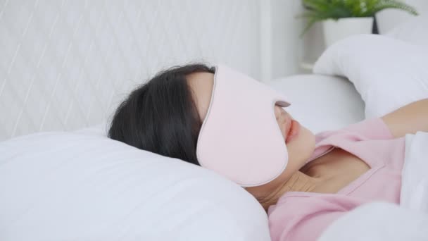 Gyönyörű fiatal ázsiai nő visel takaró szem és alszik az ágyban fejjel a párnán kényelem és a boldogság a hálószobában otthon, lány pihenni és szabadidő wellness, életmód koncepció. - Felvétel, videó