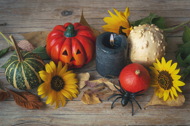 Festliche Gestaltung zu Halloween mit Jack-O-Laterne, Kürbissen, Kerze, Sonnenblumen und Spinne auf Holztisch. Herbstferienkonzept. Ansicht von oben. - Foto, Bild