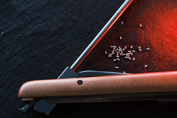 Rifle gun break in two with air pellets for hunting on cloth dark background with red light. - Photo, image