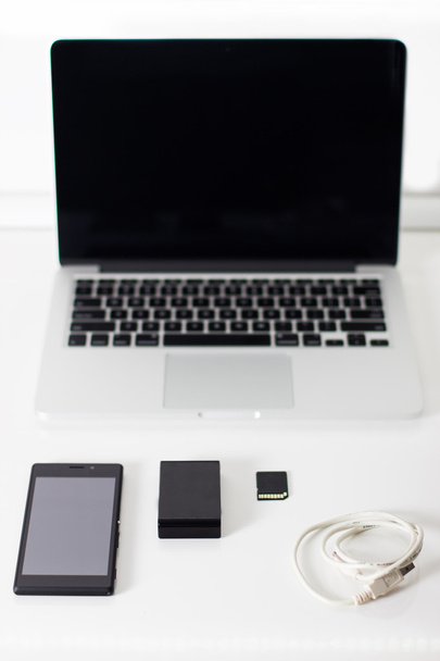 Ανοιχτό laptop με μαύρη smartphone, κάρτα μνήμης και το ποντίκι. - Φωτογραφία, εικόνα